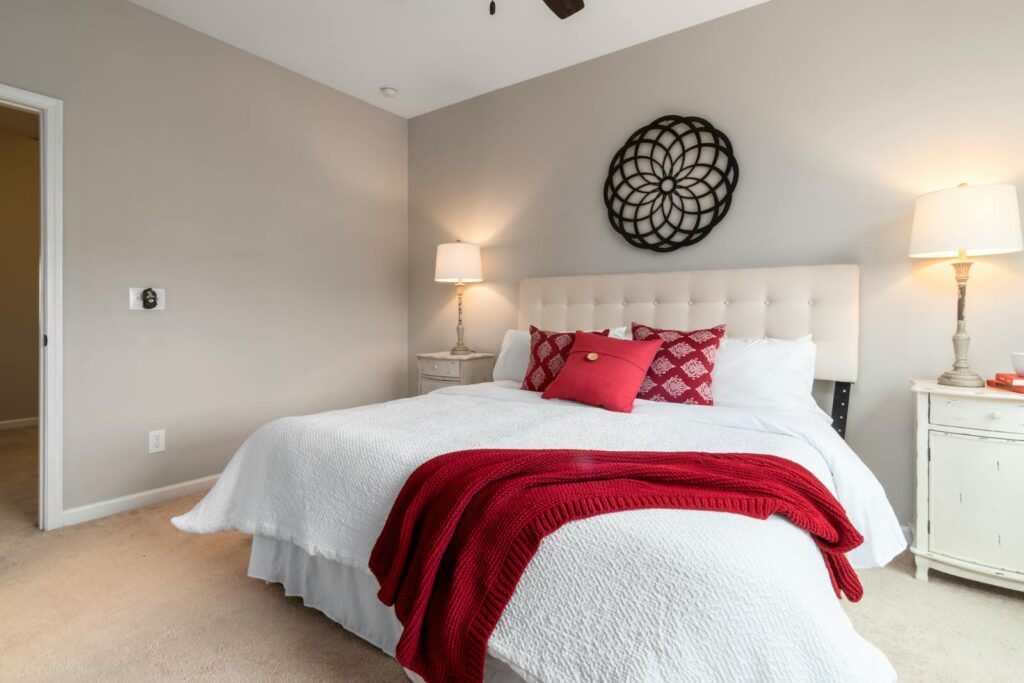 Inviting bedroom with stylish red and white decor, elegant lamps, and modern wall art.